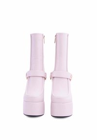 Stivali platform rosa con materiale sintetico liscio, dotati di chiusura con zip e un cinturino con dettaglio a bottone. Design robusto e alto.