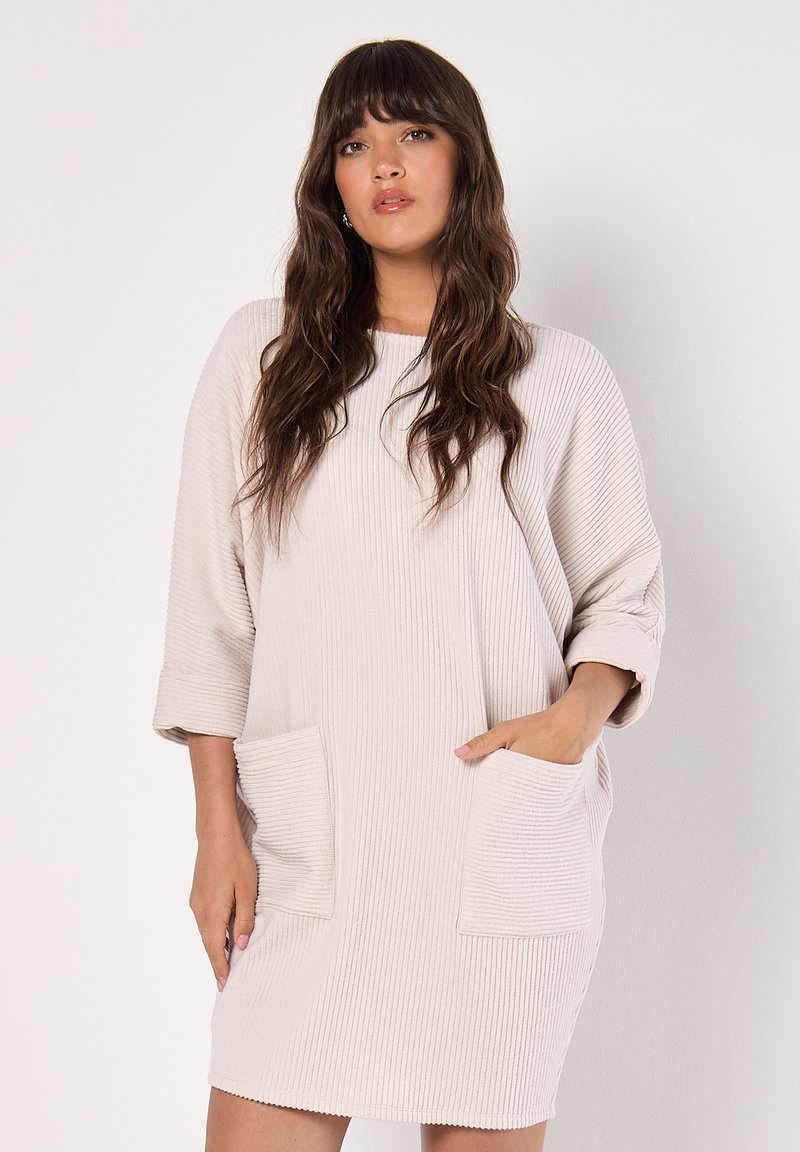 Knie-lengte ribbroek in zachte beige stof. Heeft twee voorzakken en opgerolde mouwen. Eenvoudige, ontspannen vorm met een ronde halslijn.