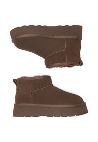 Braune Ankle Boots aus Wildleder mit einem weichen Futter aus Fell, ausgestattet mit einer flachen Gummisohle und gesteppten Akzenten an den Seiten.