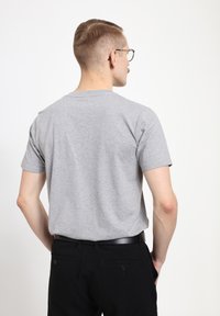 T-shirt grigio in cotone con maniche corte, scollo rotondo e vestibilità rilassata. La vista da dietro mostra una texture liscia e uno stile casual.