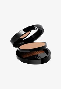 Poudre compacte de maquillage dans un boîtier noir brillant, présentant une poudre beige lisse et un support de pinceau intégré avec des poils doux.