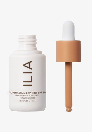ILIA Super Serum Skin Tint SPF 30 in una bottiglia bianca con testo marrone; presenta un contagocce marrone con una bulbosa bianca. 1 fl oz (30ml).