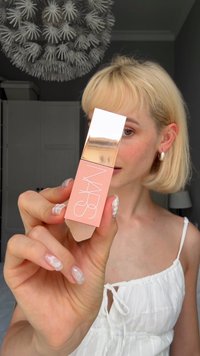 NARS Flüssiglippenstift in einem matten Pfirsichbehälter mit einem glänzenden roségoldenen Deckel. Trägt das NARS-Logo in weißer Schrift.