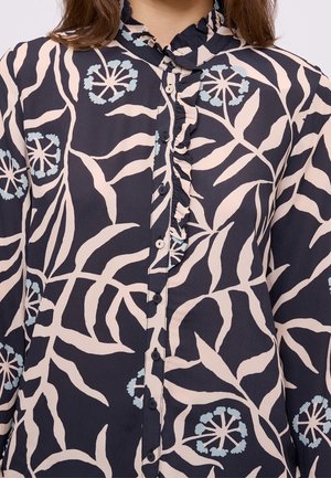 Ciemna bluzka w kwiaty z falbanianym kołnierzykiem, guzikami z przodu oraz wzorem liści i kwiatów w blado-niebieskim i kremowym na granatowym tle.
