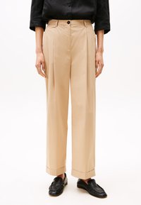 Pantaloni beige plissettati con vita alta, gamba dritta e larga, orli risvoltati, realizzati in tessuto leggero. Chiusura frontale con bottone, senza motivi.