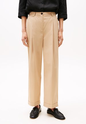 Pantaloni beige plissettati con vita alta, gamba dritta e larga, orli risvoltati, realizzati in tessuto leggero. Chiusura frontale con bottone, senza motivi.