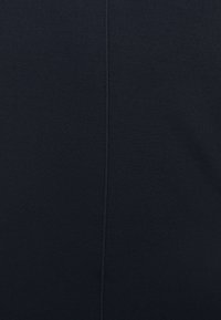 Svart elastisk tyg med en slät yta, med detalj av mittsöm. Lämplig för träningskläder eller figurnära kläddesigner.