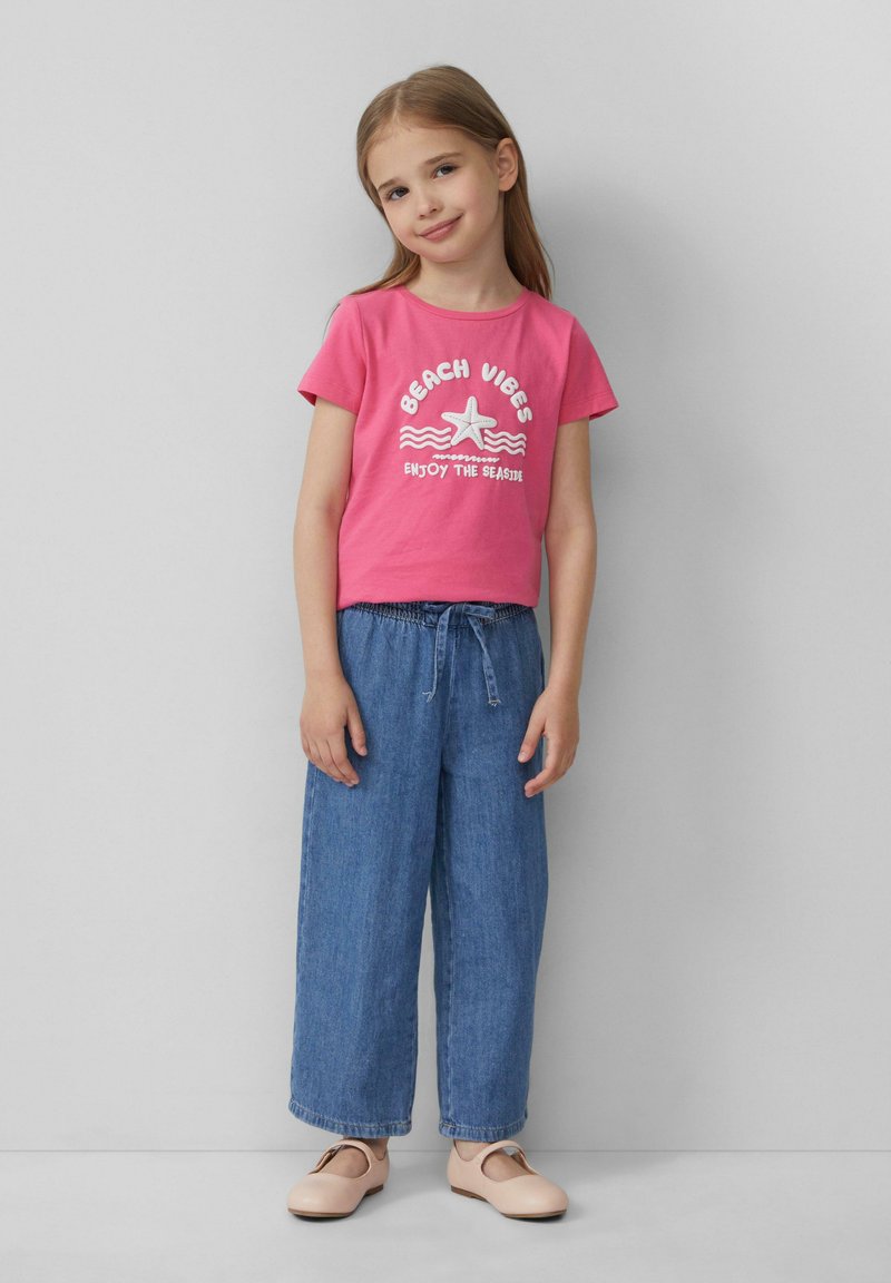 Roze katoenen T-shirt met de opdruk "BEACH VIBES", gecombineerd met losse blauwe denim broek en lichtroze schoenen. Eenvoudig, casual outfit ontwerp.