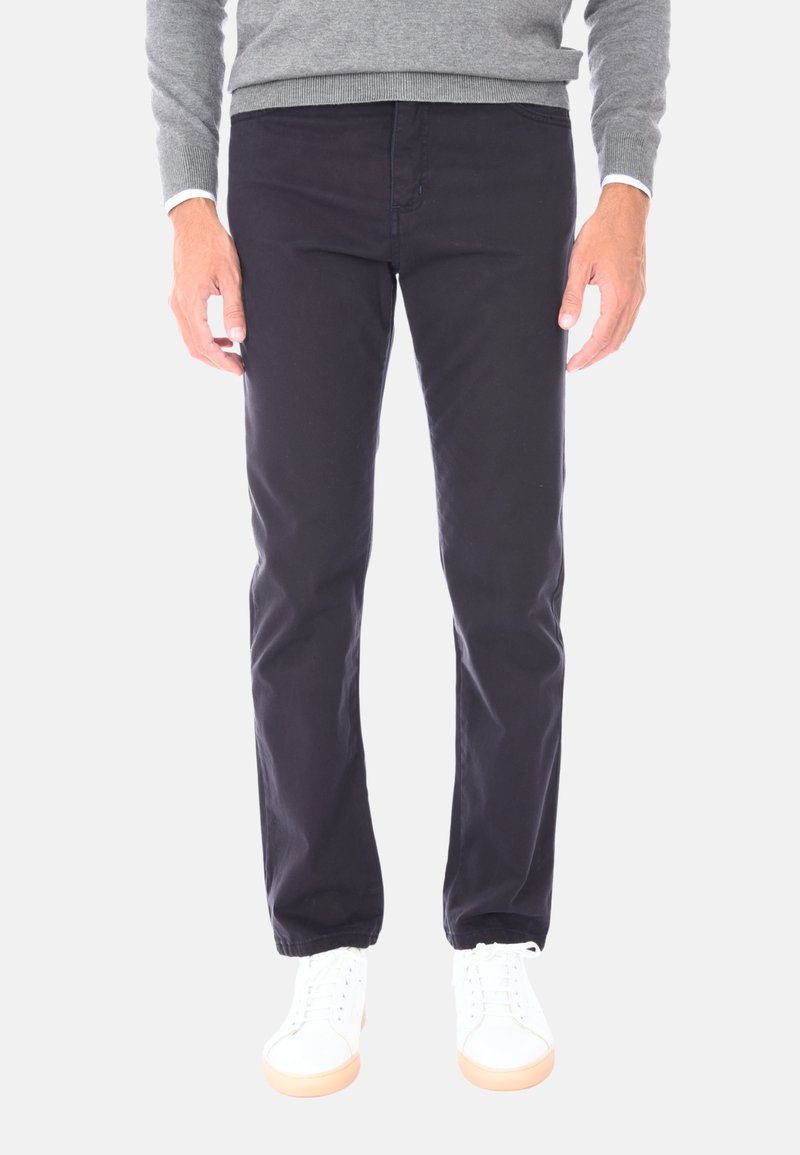 Chino in cotone blu navy con un design slim fit, caratterizzati da tasche frontali e una texture liscia, abbinati a sneakers bianche con suola in gomma.