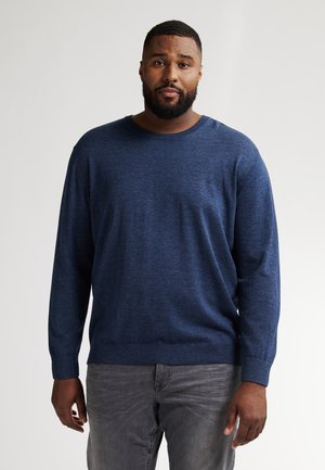 Pulover lung cu mânecă lungă de culoare bleumarin, cu guler rotund, textură moale și manșete cu model ribetat, asortat cu blugi gri. Design simplu, uniform.