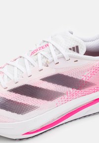 Scarpa da ginnastica bianca e rosa con tomaia in rete, strisce grafiche nere, chiusura con lacci e dettagli rosa sulla suola e nel branding.