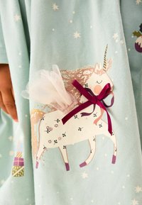 Robe bleu clair ornée d'une illustration de licorne, embellie d'une touche de tulle et d'un nœud bourgogne. Des étoiles sont dispersées en arrière-plan.