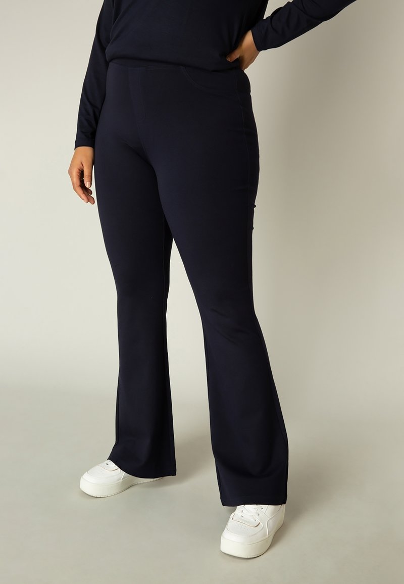 Marineblauwe flared broek van rekbaar materiaal, met een gladde textuur en een strakke pasvorm rond de taille, met minimale details.