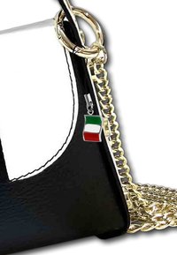 Sac en cuir noir et blanc avec une anse en chaîne dorée, arborant un petit pendentif en forme de drapeau italien attaché à un anneau en métal argenté.