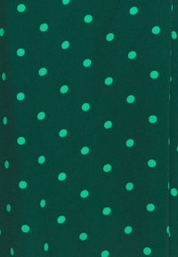 Tessuto verde con una superficie testurizzata, caratterizzato da pozzetti verdi brillanti equidistanti, creando un motivo contrastante.