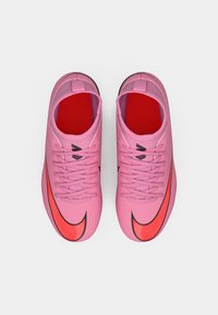 Et par rosa treningssko med røde innersåler og store røde buede swoosh-logoer, sett ovenfra mot en hvit bakgrunn.