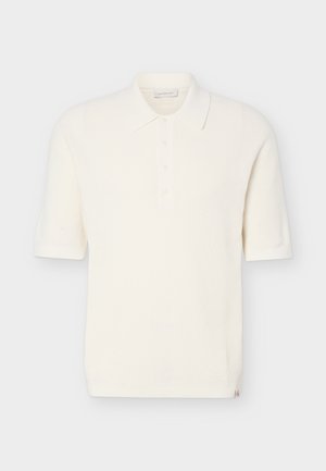 Polo in maglia bianca a maniche corte con colletto e quattro bottoni, tessuto strutturato e etichetta marchio discreta all'orlo.