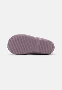 Suela de zapato de goma morada con un patrón texturizado. El diseño incluye una puntera redondeada y bordes suaves para un ajuste ceñido.