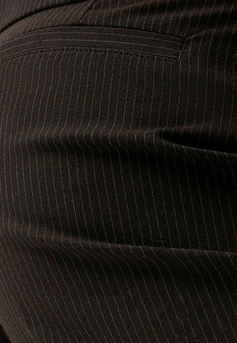 Tessuto a righe sottili marrone scuro con una texture liscia e una leggera lucentezza. Include una tasca sul retro in alto a sinistra.