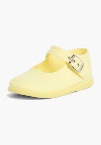 Zapato Mary Jane de lona amarilla con punta redondeada, correa ajustable con hebilla y suela de goma. Textura suave con un diseño sencillo.