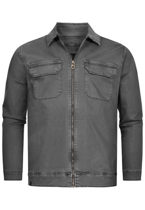 Chaqueta de mezclilla gris con cremallera en la parte delantera, cuello puntiagudo y dos bolsillos en el pecho. Textura suave con un diseño minimalista y detalles de costura.