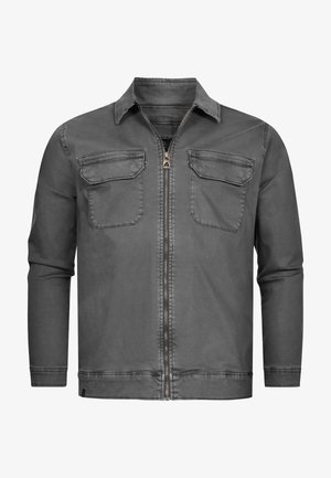 Veste en denim gris avec fermeture éclair sur le devant, col pointu et deux poches poitrine. Texture lisse avec un design minimaliste et des détails de couture.