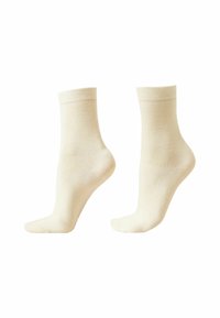 Beige bomuldsankelsokker med ribbet kant, glat tekstur og en let kontureret form, præsenteret i par.