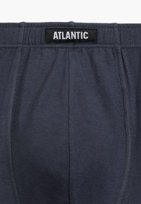 Męskie granatowe majtki z elastycznym paskiem w talii z czarną metką z napisem "ATLANTIC". Tkanina ma gładką, miękką teksturę.