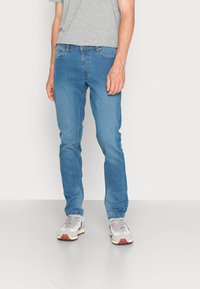 Blauwe denim jeans met een rechte snit, middelmatige wasbeurt, subtiele stikdetails en een vijf-pocket ontwerp, gecombineerd met grijze sportsneakers.