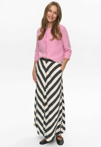 Pink kortærmet cardigan med knapper, sammen med bredbenede bukser med sort-hvide striber og sorte slip-on sko.