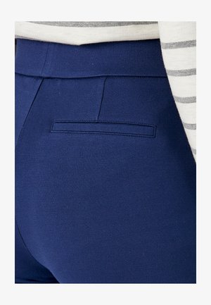Pantalones azul marino hechos de una tela elástica con un bolsillo trasero discreto y una textura suave. La cintura presenta un diseño limpio, sin costuras.