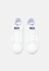 Bílé tenisky s hladkým koženým svrškem, plochými tkaničkami a kulatou špičkou. Mají jazyk s logem a minimální švy jako ozdobu.