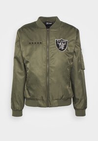 Olive green bomber jacket with ribbed cuffs and waistband. Features embroidered "RAIDERS" logo, five-star accents, and zippered sleeve pocket.