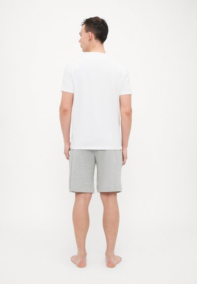 Herren T-Shirt aus weißer Baumwolle und graue Baumwollshorts. Das T-Shirt hat kurze Ärmel; die Shorts haben einen geraden Schnitt und reichen bis zum Knie.