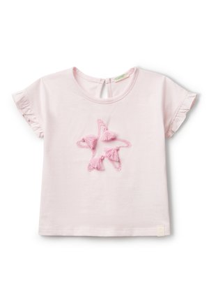T-shirt en coton rose clair avec des manches froncées, featuring un design central d'étoile brodée avec des glands roses. Détail en trou de clé au dos.
