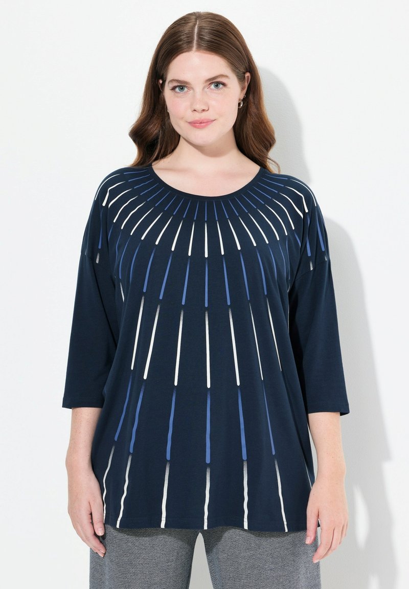 Marinblå T-shirt med rund halsringning, som har vita och blå vertikala randiga detaljer som strålar ut från mitten. Trekvartsärmar.