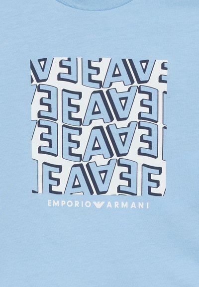 Μπλε μπλουζάκι με λευκό τετράγωνο μοτίβο που περιλαμβάνει επαναλαμβανόμενα στυλιζαρισμένα γράμματα "EA" και κείμενο "Emporio Armani" από κάτω.