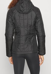 Vadderad svart pufferjacka med huva, som har en mjuk, glänsande textur, elastiska muddar och subtila sömmar för isolering.