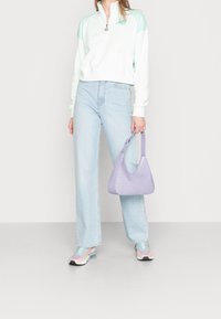 Ljusgrön och vit kvartdraget sweatshirt, ljusblå vida jeans och en lavendelfärgad handväska med krokodilprägling och böjd handtag.