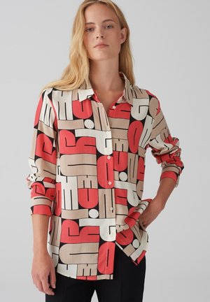 Camicia con bottoni caratterizzata da un motivo geometrico in rosso, beige, nero e bianco. Realizzata in un tessuto liscio, con maniche lunghe e colletto.