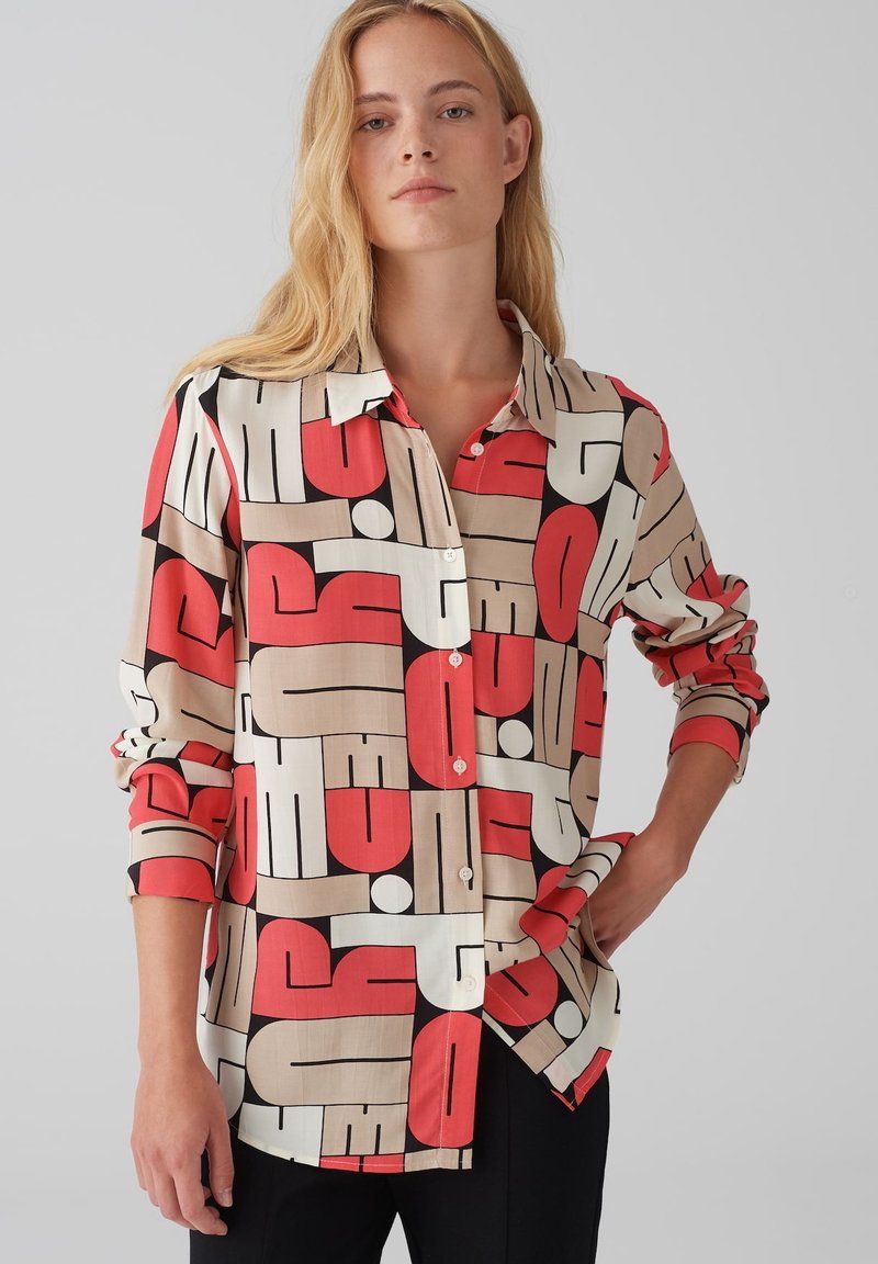 Overhemd met knopen en een geometrisch patroon in rood, beige, zwart en wit. Gemaakt van een gladde stof met lange mouwen en een kraag.