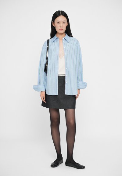Camicia a righe blu e bianche con bottoni, mini gonna grigia, collant neri e ballerine nere. Design minimalista, vestibilità rilassata, silhouette snella.