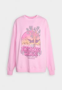 Ljusrosa sweatshirt med rund halsringning, prydd med ett grafiskt tryck av ett Joshua-träd och en ökenscen, tillsammans med stiliserad text i nederkant.
