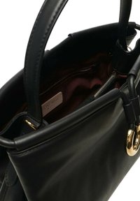 Bolso de cuero negro con doble asa, herrajes en tono dorado y forro interior burdeos que incluye un bolsillo interior con cremallera y etiqueta de la marca.