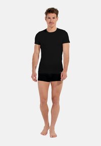 Czarny t-shirt z krótkim rękawem, wykonany z bawełny, o klasycznym okrągłym dekolcie. Dopasowany krój, gładka faktura, zestawiony z czarnymi szortami bokserskimi.