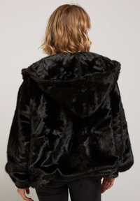 Hoodie en fausse fourrure noire avec une surface texturée, grande capuche, manches larges et coupe décontractée. Le matériau doux améliore la chaleur et le confort.