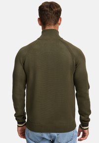 Olijfgroen pullover trui met een hoge kraag, geribbelde manchetten en zoom, heeft een gladde textuur en contrasterende gestreepte accenten op de mouwen.