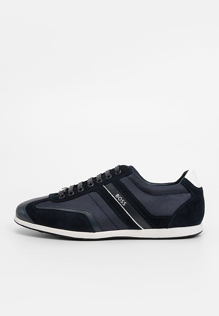 Baskets noires et gris foncé à profil bas avec un tissu texturé et des panneaux en daim, semelle blanche, design à lacets et logo "BOSS" sur le côté.