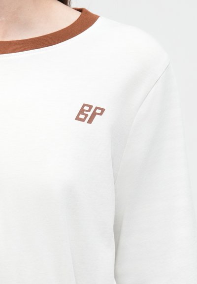 Λευκό φούτερ με καφέ ριμπ κολάρο και μικρό καφέ λογότυπο "BP" στο στήθος. Μαλακό, άνετο ύφασμα, με casual σχεδιασμό.