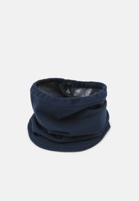 Jūras zila vilnas kakla šallīte ar gludu tekstūru un elastīgu aukliņu aizvēršanai. Elastīgs dizains, piemērots aukstam laikam.